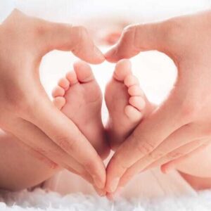 Hands in heart shape around baby feet