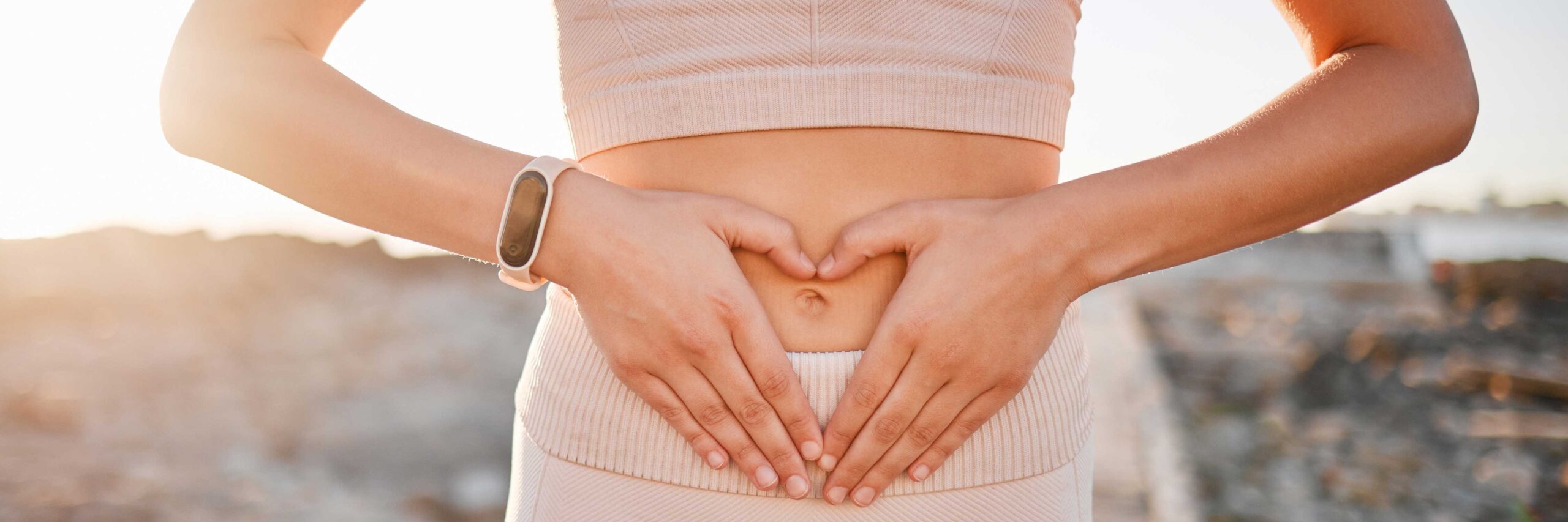 Women with blocked fallopian tubes hold her hands in a heart shape over her abdomen | Envita Fertility Center | Laguna Hills & Orange County, CA