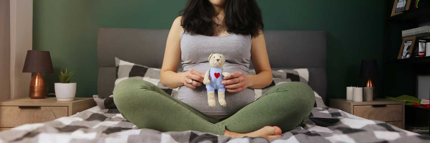 A gestational carrier holds a teddy bear | Envita Fertility Center | Laguna Hills & Orange County, CA